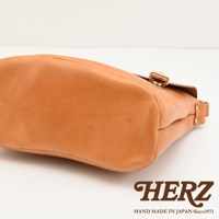 日本HERZ職人手作皮革雙扣旅行郵差包CK-153，以Latigo牛皮革製成，呈現職人手作質感，圖片呈現包款底部側面，可見其立體剪裁與雙插釦設計。