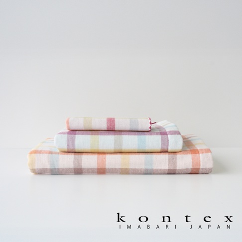 KONTEX IMABARI JAPAN 的三條馬德拉斯格紋毛巾堆疊，以柔和的粉色、黃色、藍色和橘色條紋為特色，背景為白色。