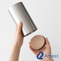 一隻手拿著一個銀色不鏽鋼餐具收納筒，另一隻手拿著一個木質圓形蓋子，蓋子邊緣有黑色矽膠圈。