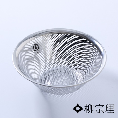 一個銀色不鏽鋼製成的圓形瀝水盆，盆身佈滿規則的細小圓孔，邊緣光滑，盆底有少量陰影，右下角有黑色標誌和中文文字。