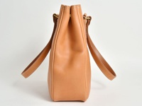 淺棕色皮革托特包，側邊視角，展示其光滑的皮革材質、縫線細節及提把。