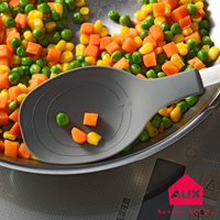 一個灰色不沾桌拌炒量匙，置於裝有豌豆、玉米粒和胡蘿蔔塊的鍋中，量匙內有刻度標示。