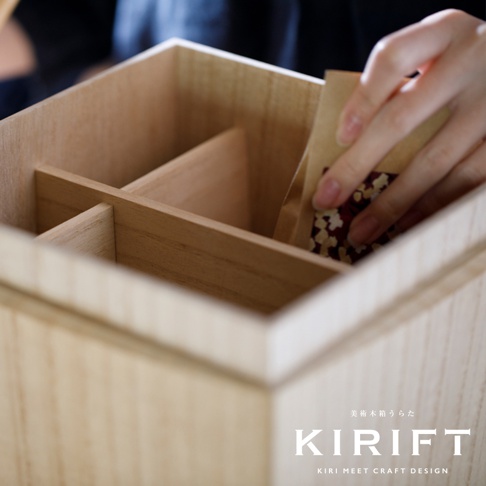 淺色桐木調濕分隔收納箱，內部有十字隔板，一隻手正在放入一個小紙袋。