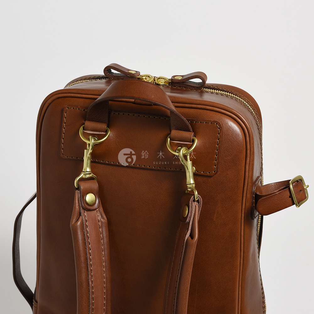 職人手作皮革兩用多功能後背包 R-66，棕褐色，設有頂部提把、可拆卸式肩帶掛鉤、拉鍊開口及側邊扣帶。