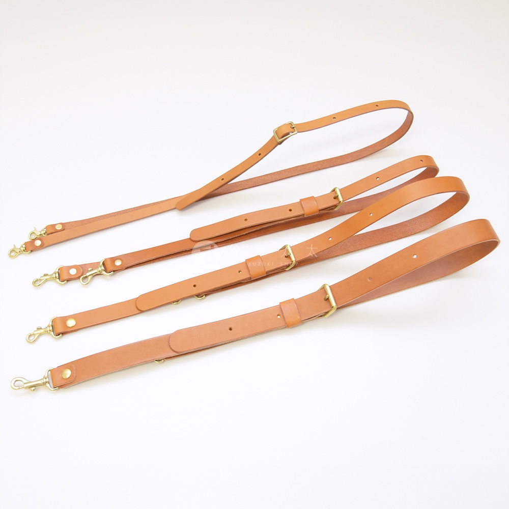 圖片中的文字總數為 14 字，未超過 50 字，因此採用視覺描述模式。 四條棕色皮革製成的肩背帶，帶有金色金屬掛鉤和調整扣，整齊排列於白色背景上。