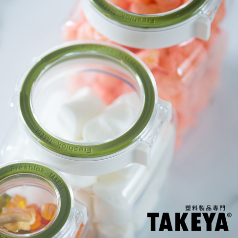 三個帶有綠色密封圈的透明角型收納罐，其中兩個罐子裝有白色棉花糖，另一個罐子裝有橘色塊狀物。