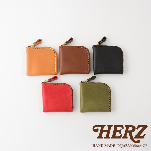 五款不同顏色的日本HERZ職人手作皮革分隔零錢包，分別以淺棕、深棕、黑色、紅色與橄欖綠色呈現，包身外型小巧精緻，採用拉鍊封口設計並配有皮革拉環，右下角印有HERZ品牌字樣與日本手工製作標記。