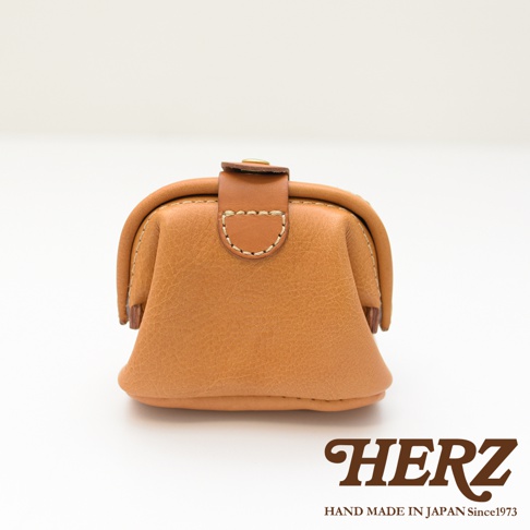 職人手作皮革口金化妝包 KF-143 S，呈現焦糖棕色，使用柔軟的天然皮革製作，具有經典的口金開合設計和精緻的縫線細節。