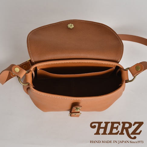 HERZ 職人手作皮革休閒旅行馬鞍包，展示其精緻的縫線工藝和溫潤的皮革質感，內部隔層清晰可見。