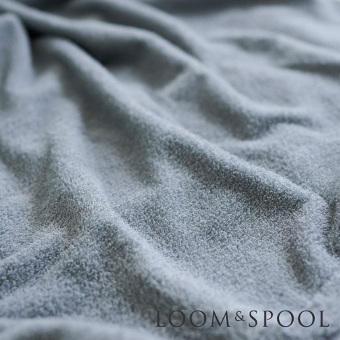 柔軟的灰色毛巾，帶有細緻的紋理和褶皺，右下角有 LOOM & SPOOL 品牌標誌