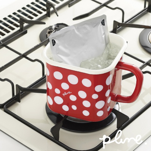 紅色琺瑯保鮮罐，帶有白色圓點圖案，罐身有紅色把手。罐內盛有水，並浸入一個銀色包裝袋。保鮮罐置於爐灶上。