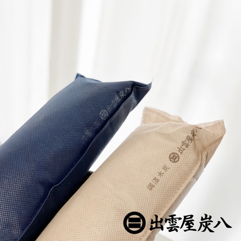 兩個長條狀的除濕炭包，一個深藍色，一個淺褐色，皆印有「出雲屋炭八」的品牌標誌和文字。