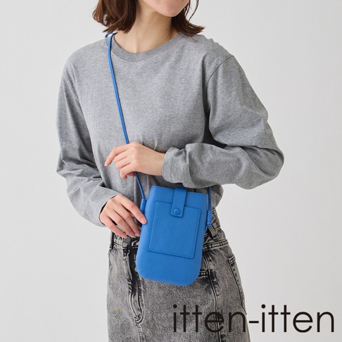 itten-itten BOLLA 義大利皮革散步手機包，亮藍色，正面有一個小口袋和一個鈕扣開合，搭配灰色牛仔褲。