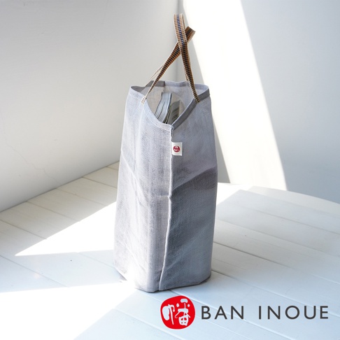 一個灰色的網狀提把收納袋，帶有條紋織帶提把，袋口處有紅色小圓標。