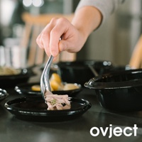 一隻手正用金屬夾子夾取煮熟的肉塊，放在一個光滑的黑色琺瑯小碗裡。背景有幾個同樣的黑色琺瑯鍋具和一些檸檬片。