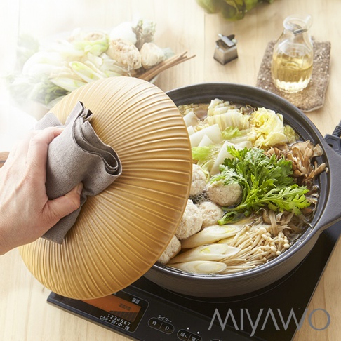 IH系列6.5號耐溫差陶土湯鍋，內含豐富的燉煮食材，如雞肉丸、大白菜、青蔥和菇類，鍋蓋為金黃色陶土材質，表面有放射狀紋路，由手持灰色布巾準備開蓋。