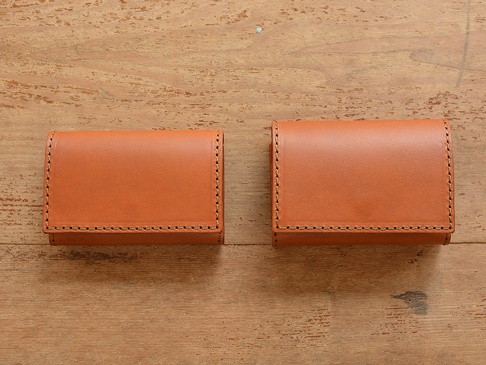 兩個淺棕色牛皮證件夾，以縫線裝飾邊緣，放置在木紋背景上。