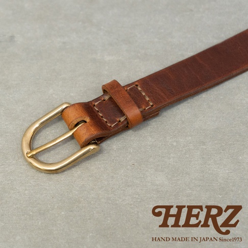 日本HERZ職人手作皮革Organ英倫皮帶，金屬皮帶扣和焦糖色牛皮材質，近拍視角，右下角有HERZ品牌標誌。