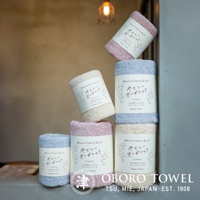 堆疊的有機棉浴巾，呈現粉紅色、淺藍色和米白色，質地柔軟，帶有日文標籤。