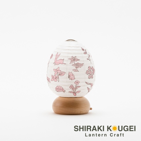一個蛋形白色紙質提燈，燈罩上印有粉色兔子、松鼠、刺蝟及花卉圖案，燈座為圓形淺木色木製底座。