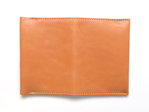 淺棕色皮革翻蓋記事本書套，簡潔的設計，邊緣有縫線裝飾。