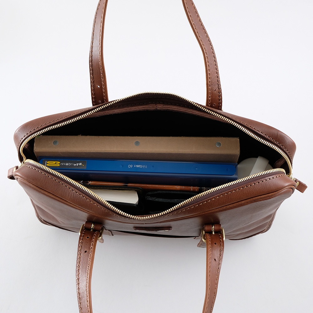 棕色皮革製成的手提公事包，內部裝有筆記本、文件夾和電腦滑鼠。