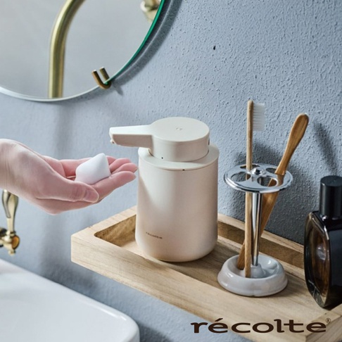 recolte 泡泡給皂機旁擺放著竹製牙刷架，上面有兩支牙刷，架旁有一個深色瓶狀物，旁邊還有一個木製托盤。