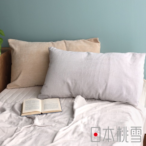 兩款長方形枕頭，一個為淺米色絲絨材質，另一個為淺灰色毛巾布材質，放置於床上，一旁有打開的書本。
