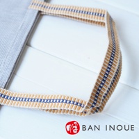 灰色布質提把蔬果收納袋，提把織帶為米白色，帶有藍色與黃褐色直條紋，質料為棉麻。