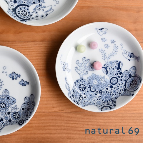 兩個白色陶瓷小碟，分別飾有藍色線條描繪的海洋生物圖案，包括魚、珊瑚和海星。其中一個碟子上有三顆粉色、黃綠色的糖果。