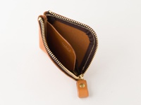 淺棕色皮革製成、拉鍊打開的零錢包，內部有兩個隔層，外側有一個皮革拉環。