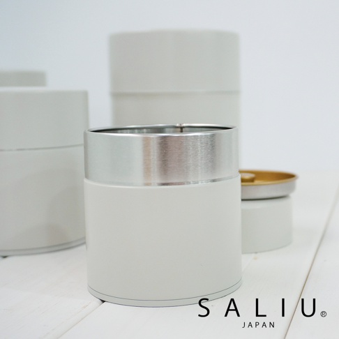 簡約風格的白色錫製圓筒茶葉罐，頂部飾有銀色金屬環，罐身光滑，可見多個同款茶葉罐。
