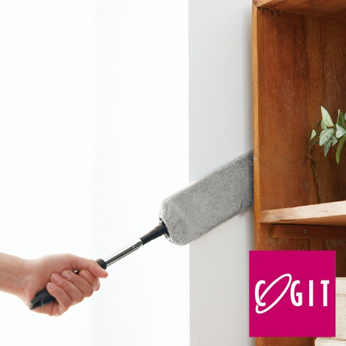 一隻手握住帶有灰色纖維頭的伸縮式清潔刷，清潔一個木製架子的狹窄縫隙。