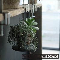 鐵製可夾式小物高低桌，以金屬夾固定於木質層板，懸掛著兩個盆栽，其中一個為枝條細長的綠色植物，另一個為肥厚葉片的綠色植物，整體呈現簡約自然風格。