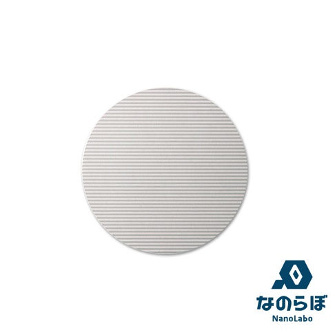 圓形淺灰色珪藻土置物墊，表面有細緻的平行紋路，角落有「nanolabo」的藍色六角形與日文 logo。