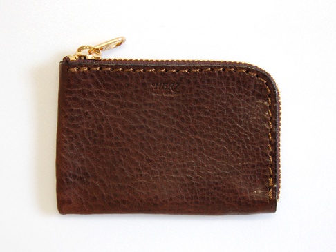 棕色皮革L型拉鍊卡片夾，表面帶有自然的紋理，金色拉鍊頭，手工縫線。