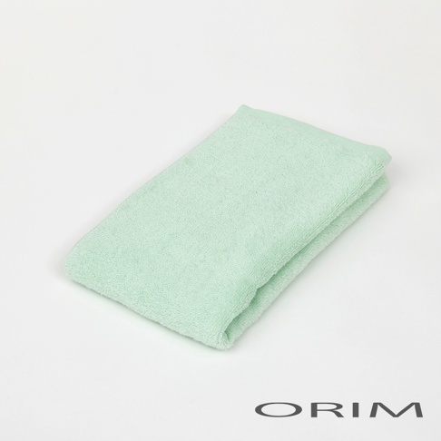 一條淡綠色的迷你毛巾，材質柔軟，呈現出細緻的絨毛感，毛巾對折放置於白色背景上。