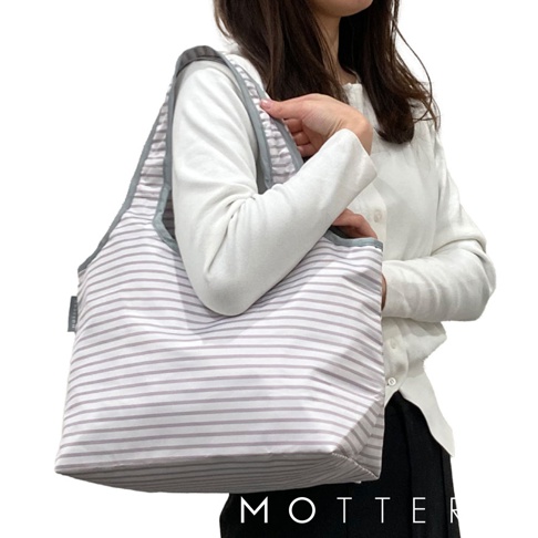 一位女性持著一個白色底、紫色細條紋的摺疊保冷托特袋，包包有灰色滾邊與提把。