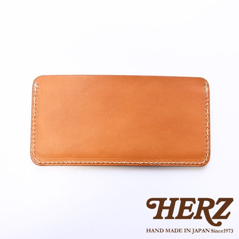 日本職人品牌 HERZ 手作皮革紙鈔收納夾，採用淺棕色 Latigo 軟皮革製成，矩形外觀簡約大方，邊緣以淺色線材手工縫製呈現細緻質感，整體呈現溫潤自然的光澤感。