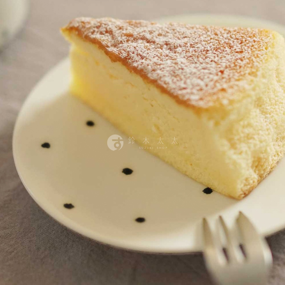 日式美濃燒白色陶瓷點心盤，盤面飾有黑色手繪圓點，盤中擺放著一塊撒有糖粉的香濃起司蛋糕。