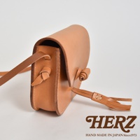 職人手作皮革流蘇側背包，淺棕色天然皮革材質，設計簡約，附有可調整的皮革背帶與裝飾性流蘇，風格自然。