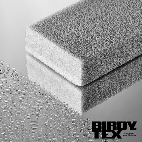 光滑鏡面上放置著一個專業玻璃杯耐用海綿刷，海綿刷為灰色，帶有細密的孔洞，一側為白色較細緻的海綿。