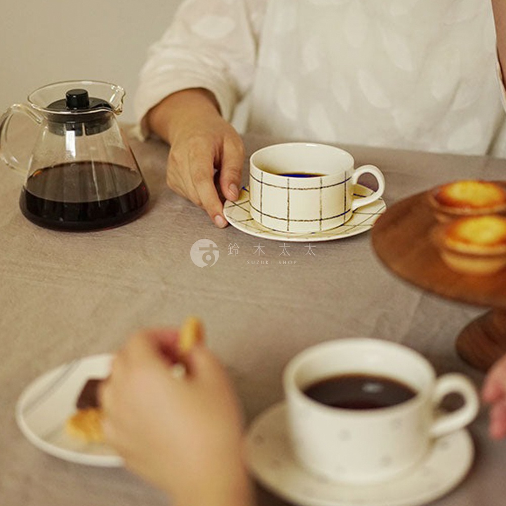 三款美濃燒手繪點心盤，其中一款為米白盤面搭配黑色細格紋，另一款為白色盤面點綴黑色小圓點。盤上盛有咖啡杯與小點心，一旁擺放著玻璃咖啡壺。
