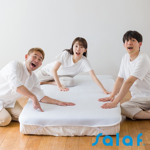 SALAF COOL 極致涼感透氣單人睡墊，白色，表面有細緻紋理，附有固定鬆緊帶。三位身著白色服飾的年輕人驚喜地圍繞在睡墊周圍，雙手伸向睡墊。