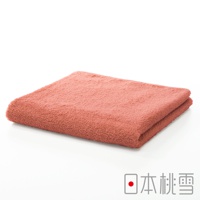 一條珊瑚粉色精梳棉飯店毛巾，質地柔軟，對折展示。