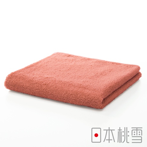 一條珊瑚粉色精梳棉飯店毛巾，質地柔軟，對折展示。