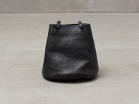 黑色皮革抽繩水桶包，帶有兩個短提把，可肩背或手提。