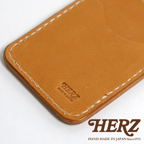 HERZ 名片夾，採用 tan 色皮革製作，車縫線清晰，壓印有 HERZ 品牌標誌及 MADE IN JAPAN 字樣。