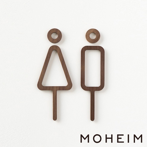 一對深棕色木製男女標示牌，左邊為女性符號（三角形上方帶圓圈），右邊為男性符號（長方形上方帶圓圈）。