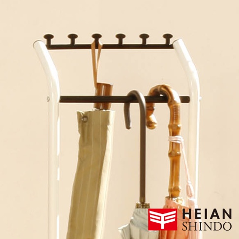 直立吊掛傘架 H-3，白色框架搭配深棕色掛鉤。傘架上吊掛著兩支傘，一支是米白色條紋傘，另一支是木質握把的淺粉色傘，傘架底部還有一個銀灰色傘。